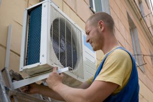 Young setup man installs the new air conditioner for office.